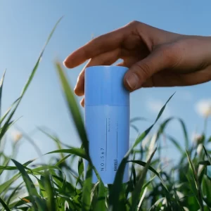 Déodorant 567 pour homme de Bargello inspiré de Sauvage, tenu à la main au milieu de hautes herbes vertes dans une ambiance fraîche et naturelle.